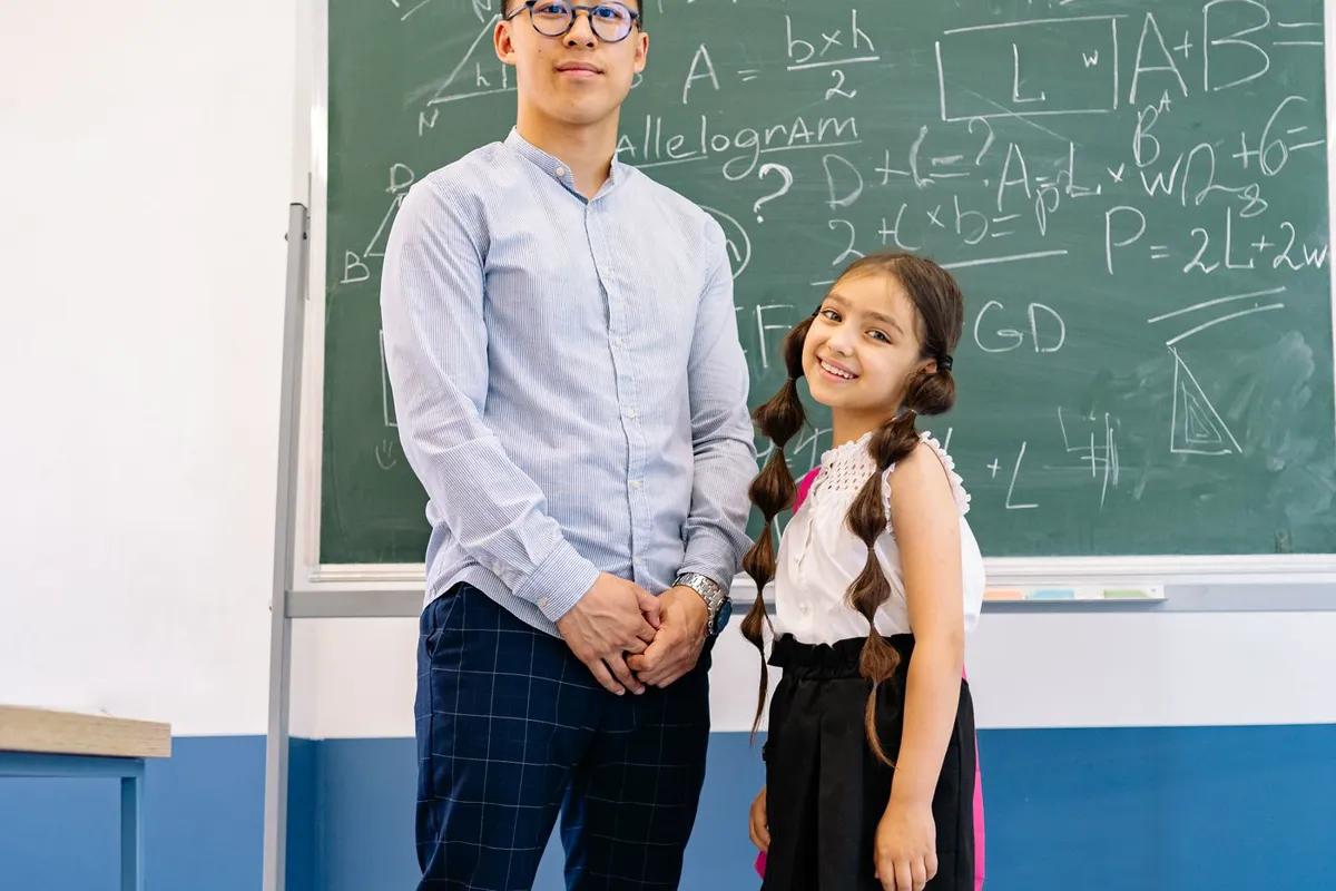 A teacher supporting a pupil at a classroom board