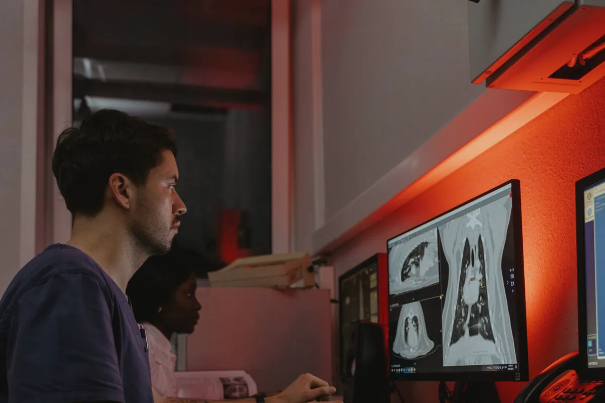 Clinicians reviewing diagnostic scans on reporting monitors